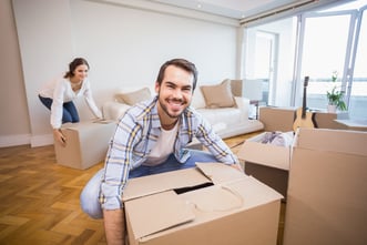 a man smiling holding a box and wife is doing the same, home shifting 